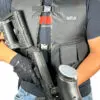 Person holding a paintball gun and hopper.
