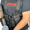 Man wearing a tactical vest and holding a gun.