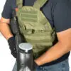 Person wearing a tactical vest and holding a paintball gun.