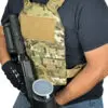 Person wearing tactical vest and holding a gun.