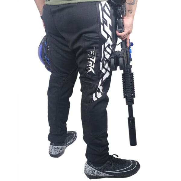 Person in paintball pants holding gun.