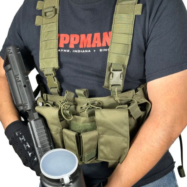 Man wearing tactical vest and holding gun.