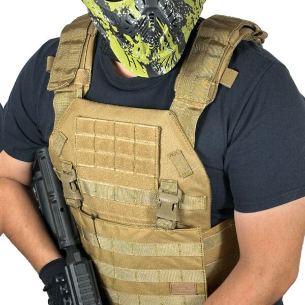 Person wearing tactical vest and holding a gun.