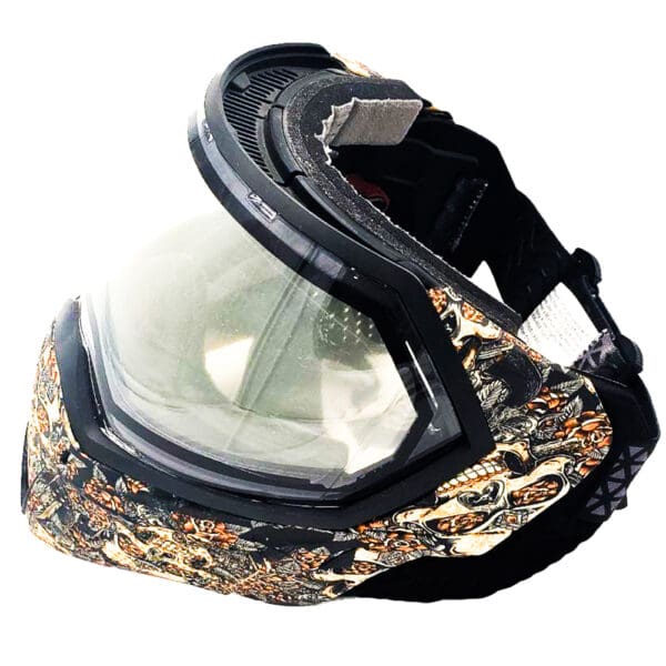 Black and gold paintball mask with skull design.